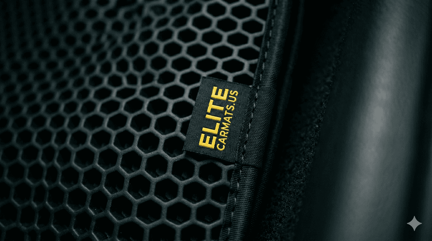 Close-up of the EVA mat edge: yellow ELITECARMATS.US brand tag stitched into the fabric trim against the black honeycomb texture